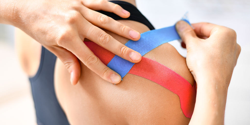 Behandlung mit blauem und rotfarbenem Klebeband auf dem verletzten Arm des Patienten.