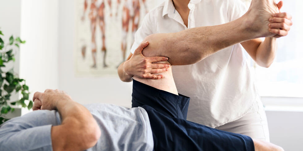 Physiotherapeuten, der das Bein eines Patienten massiert und knetet, sorgt für die medizinische Versorgung der Bänder.