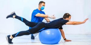 Physiotherapeut mit Patient der Gleichgewichtsübungen auf einem Gymnastikball macht