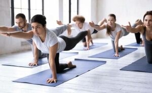 Rehasportklasse im Fitnessraum bei Gleichgewichtsübungen auf Yogamatte