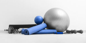 Unterschiedliche Physiotherapie-Geräte: Gymnastikball, Yoga-Matten, Sprungseile, Hanteln