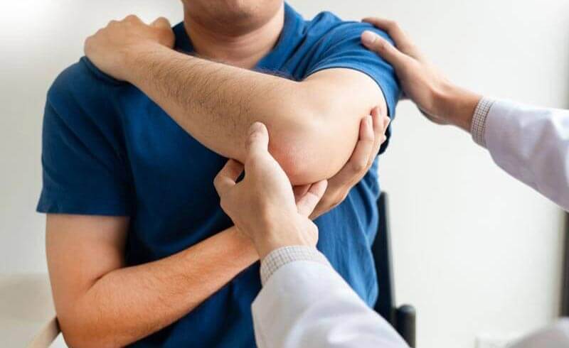 Physiotherapeut behandelt die verletzte Schulter eines Patienten