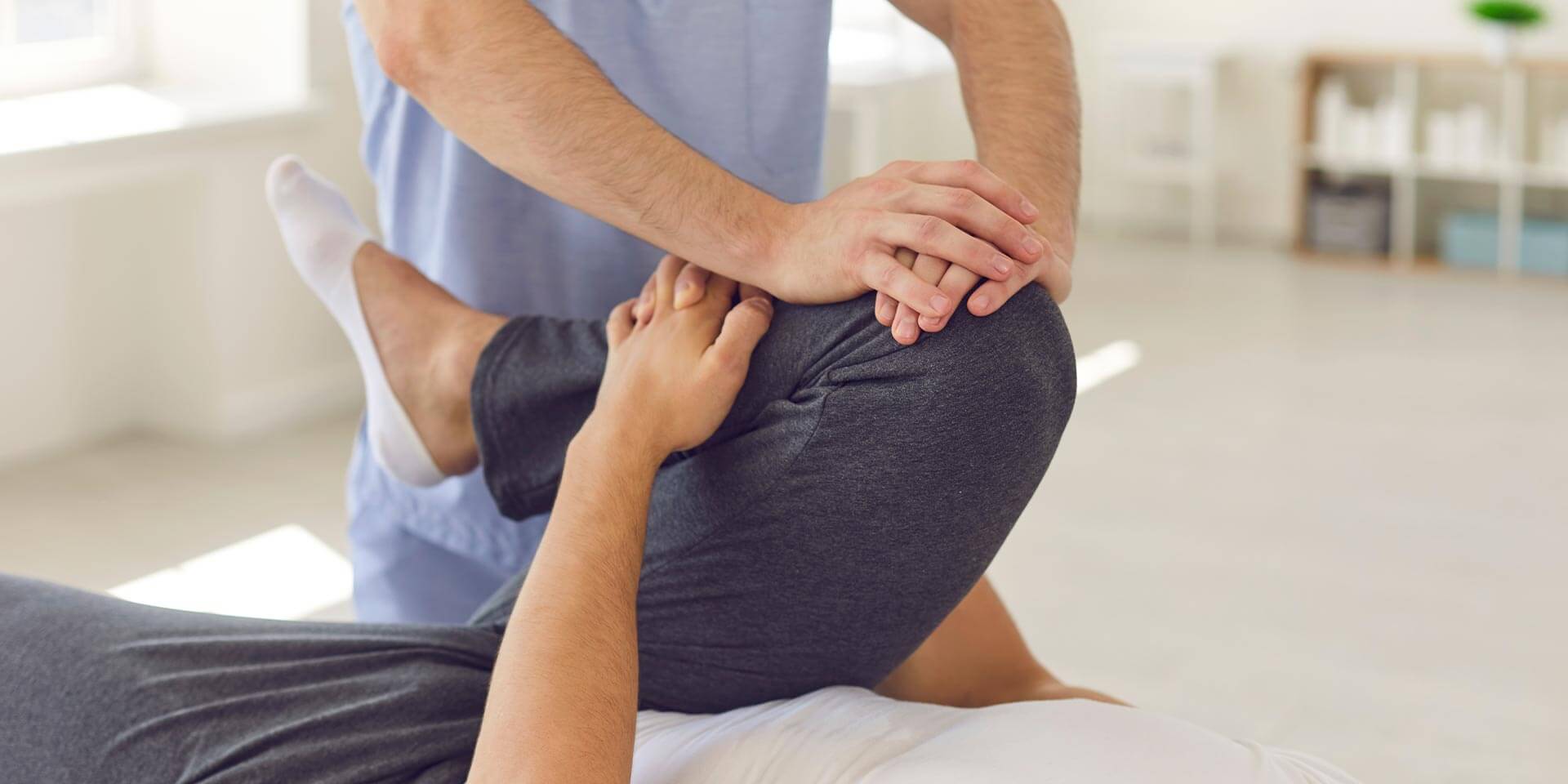 Physiotherapeut, der das Bein eines Patienten massiert und knetet. Konzept der Rehabilitation und Erholung nach Verletzungen der Beine.