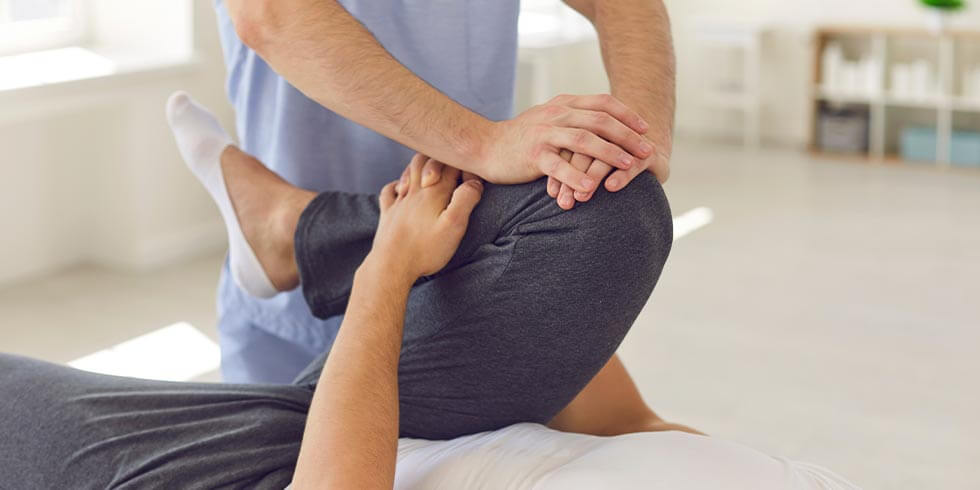 Physiotherapeut, der das Bein eines Patienten massiert und knetet. Konzept der Rehabilitation und Erholung nach Verletzungen der Beine.