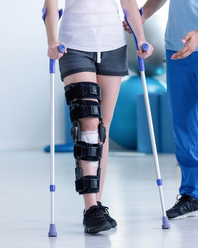 Sportphysiotherapeut und Patient mit Beinverletzung während des Trainings mit Krücken