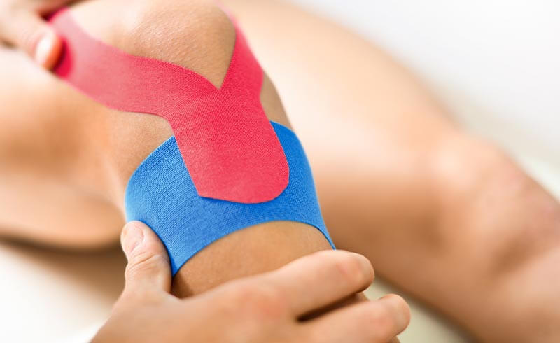 Therapeut tapt Knie eines Patienten