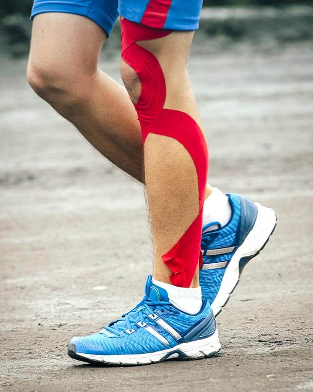 Sportler mit getapten Unterschenkel und Kniegelenk beim Laufen