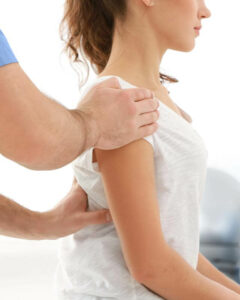 Physiotherapeut bearbeitet Schulter einer Patientin