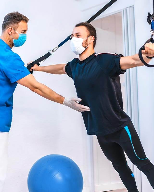 Physiotherapeut hilft einem Patienten, indem er sich mit Gummibändern auf den Kopf streckt. 