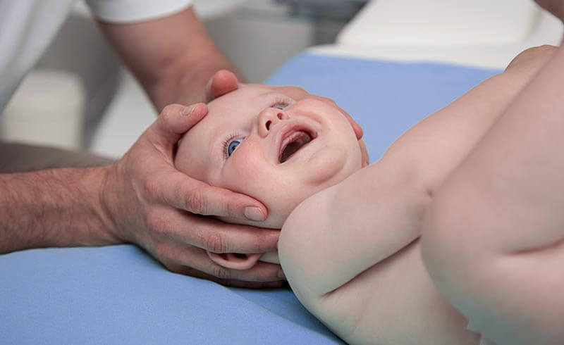 Physiotherapeut prüft Kopf eines Babys
