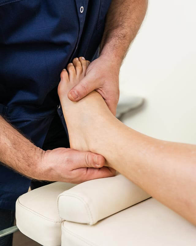 Physiotherapeut massiert Fuß einer Patientin